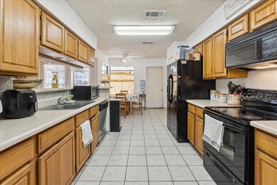 Kitchen with black appliances, sink, light tile pa