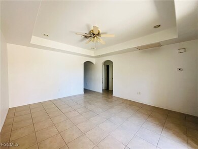 Unfurnished room with a tray ceiling, arched walkways, and light tile patterned flooring