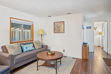Living room with dark wood-type flooring and baseb