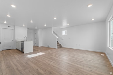 Unfurnished living room with light wood-style flooring, stairway, and recessed lighting