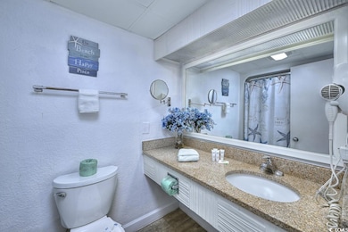 Full bath with a textured wall, toilet, wood finis