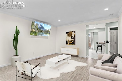 Living room with plenty of natural light, light wood-style flooring, recessed lighting, and ornamental molding=- virtually staged