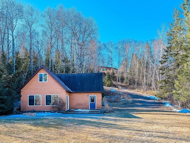 View of front of property with a wooded view and a