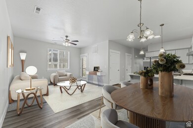 Dining area & living room (Virtually staged) with wood finished floors, a ceiling fan, a textured ceiling, and a chandelier