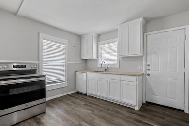 Kitchen featuring electric range, a sink, dark woo