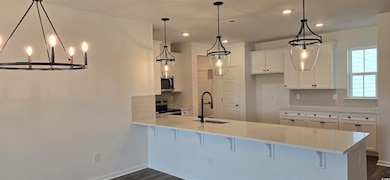 Kitchen featuring a sink, appliances with stainless steel finishes, tasteful backsplash, a peninsula, and light countertops