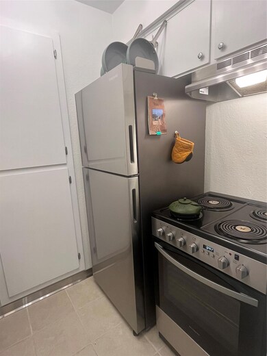 Kitchen featuring stove, range hood, white cabine