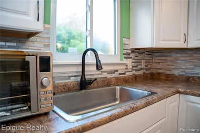 Kitchen view of white cabinets, backsplash, and dark countertops