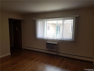Empty room featuring a baseboard radiator, dark wood-style floors, and a wall mounted air conditioner
