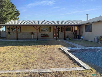 View of front of home with brick siding, a front yard, covered porch, and a metal roof