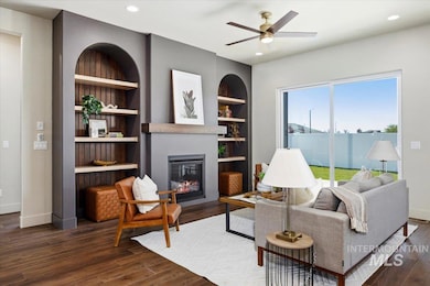 Living room featuring a glass covered fireplace, wood finished floors, ceiling fan, built in shelves, and recessed lighting