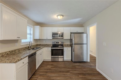 Kitchen featuring stainless steel appliances, a sink, and white cabinets