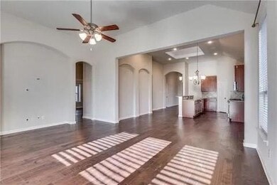 Unfurnished living room featuring dark hardwood / wood-style flooring, high vaulted ceiling, and ceiling fan with notable chandelier