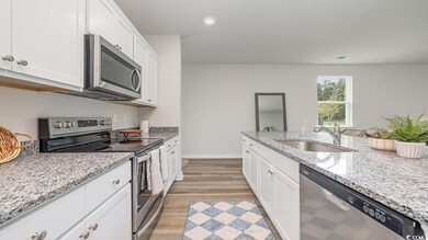 Kitchen with appliances with stainless steel finishes, sink, light hardwood / wood-style flooring, light stone counters, and white cabinets