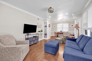 Living area featuring wood finished floors, a chandelier, ornamental molding, recessed lighting, and baseboards