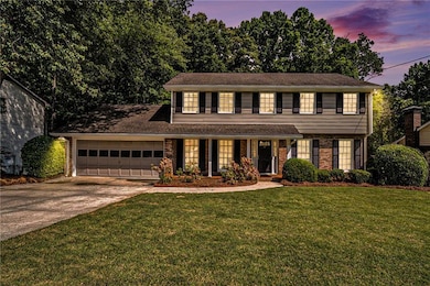 View of front facade with a garage, driveway, a lawn, brick siding, and a porch