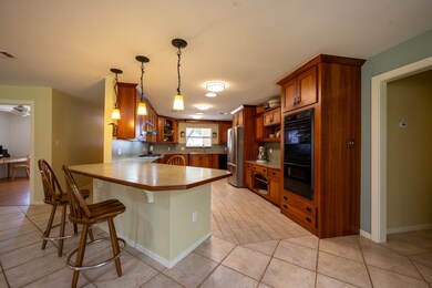 3 / 50View into the kitchen over breakfast bar with stools. To the left is the entryway, and further to the left a peak into the den/media room. Lights and skylights help keep this room bright.