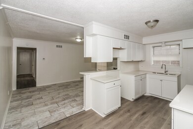 Kitchen featuring white cabinetry, light wood-style floors, crown molding, and a textured ceiling
