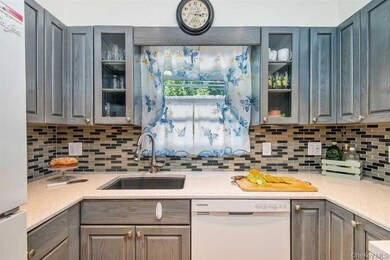 Kitchen featuring dishwasher, refrigerator, glass insert cabinets, decorative backsplash, and gray cabinets
