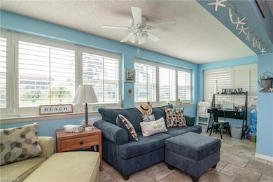Living area with a ceiling fan, a textured ceiling, tile patterned flooring, and rail lighting