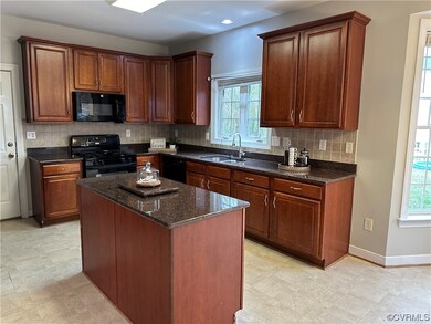 Kitchen with light tile floors, sink, dark stone c