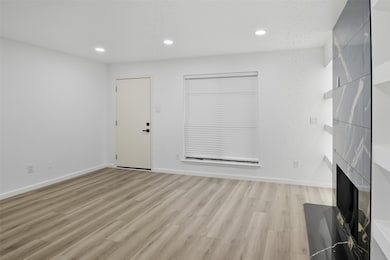 Unfurnished living room featuring light wood-type flooring, recessed lighting, and a large fireplace