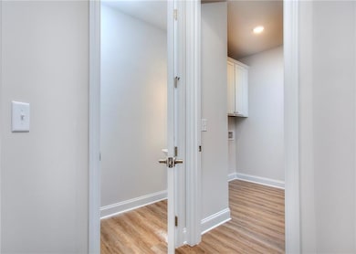 Corridor featuring light wood-style finished floors, baseboards, and recessed lighting