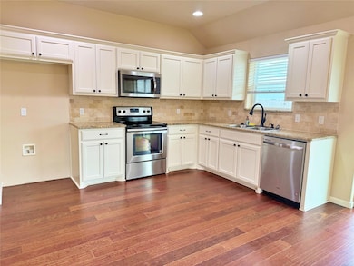 Kitchen featuring white cabinets, light stone countertops, sink, and stainless steel appliances