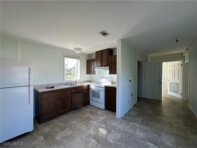 Kitchen with dark brown cabinets, white appliances, and sink
