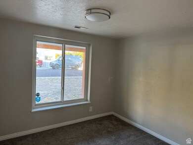 Spare room featuring dark colored carpet and a textured ceiling