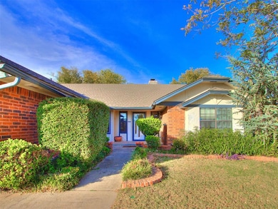 View of front facade featuring brick siding, a front yard, a chimney, and a shingled roof