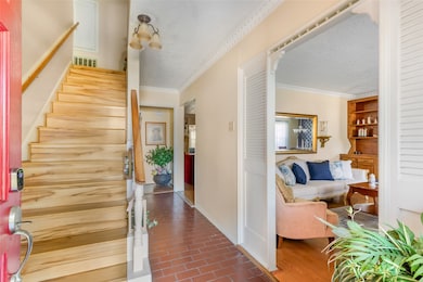 Welcome to a cozy home featuring a warm entrance with natural wood stairs and a charming living area. The space is inviting with soft lighting, tasteful decor, and a blend of tile and hardwood flooring. Perfect for a comfortable and welcoming atmosphere.
