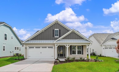 View of front facade with board and batten siding, covered porch, a standing seam roof, a metal roof, and driveway