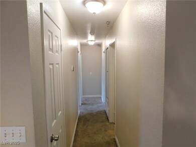 Hall featuring a textured wall, baseboards, and ca