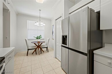 Kitchen featuring light countertops, stainless steel appliances, white cabinetry, ornamental molding, and pendant lighting