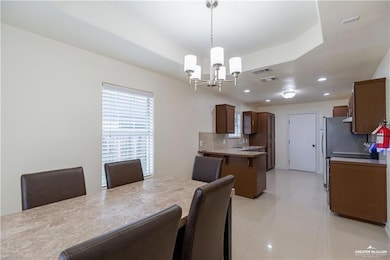 Dining room with a chandelier, recessed lighting, light tile patterned floors, and a raised ceiling