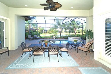 Covered lanai with brick pavers overlooks the pool and lake beyond.