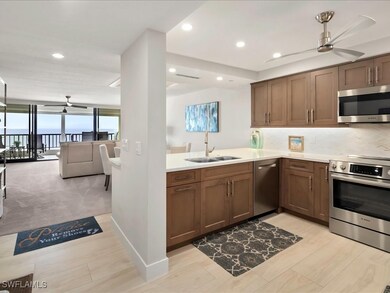 Kitchen with ceiling fan, stainless steel appliances, decorative backsplash, open floor plan, and light stone countertops