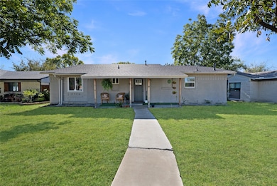 View of front of property featuring a front lawn, covered porch, brick siding, and roof with shingles