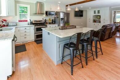 Lots of storage with oversized island, double oven range, view of custom book cases in the den.