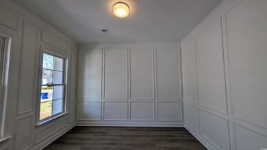 Empty room featuring a decorative wall and dark wood-style floors