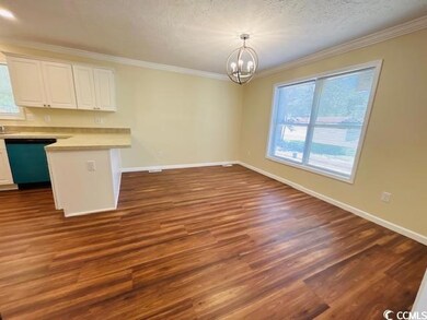 Unfurnished dining area featuring a chandelier, crown molding, dark wood-style floors, and baseboards