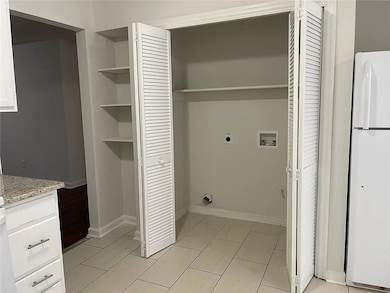 Laundry area with hookup for an electric dryer, washer hookup, light tile patterned flooring, and baseboards