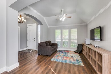 Living room with ornamental molding, lofted ceiling, ceiling fan with notable chandelier, and dark hardwood / wood-style flooring
