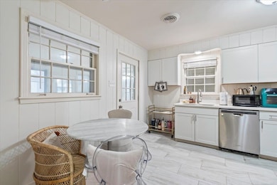 Kitchen featuring stainless steel dishwasher, sink, and white cabinets