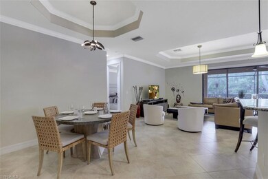 Dining area with a raised ceiling, crown molding, a chandelier, and light tile patterned floors