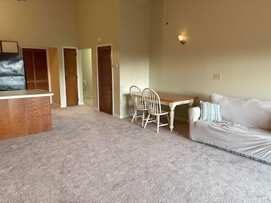 Living area with a high ceiling, carpet flooring, and baseboards