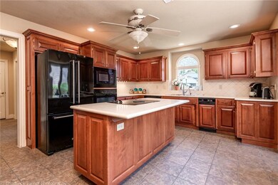 Large open kitchen with black appliances, stained