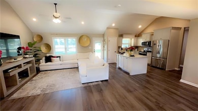 Living room featuring lofted ceiling, recessed lighting, dark wood-style flooring, and ceiling fan