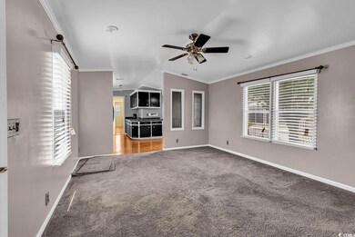 Unfurnished living room with carpet floors, a ceiling fan, baseboards, crown molding, and lofted ceiling